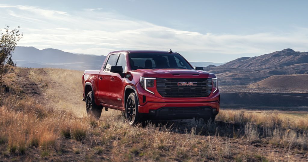A GMC Sierra 1500 driving off-road through a dry field