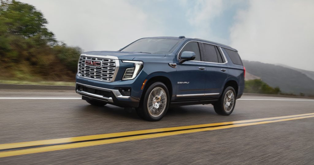 A GMC Yukon Denali driving on an empty road.